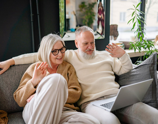 Couple assit sur un divan devant un ordinateur portable