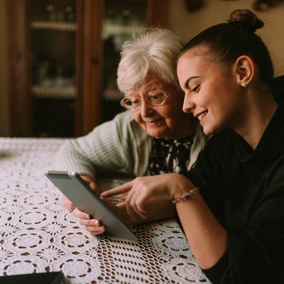 Jeune femme aidant une femme âgé a utiliser une tablet électronique