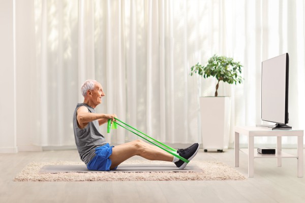 Homme âgé qui fait de l'exercise devant une télévision